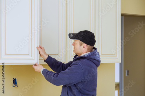 Rear view of serviceman fixing cabinet with kitchen