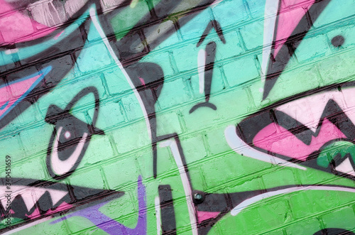 Abstract colorful fragment of graffiti paintings on old brick wall in green colors. Street art composition with parts of unwritten letters and multicolored stains. Subcultural background photo