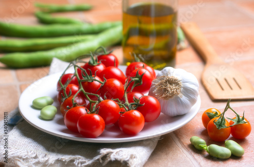 cherry tomato, broad beans and garlic in white plate - closeup