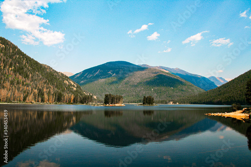 Mountain lake with blue sky and white puffy clouds and beautiful reflections on the water