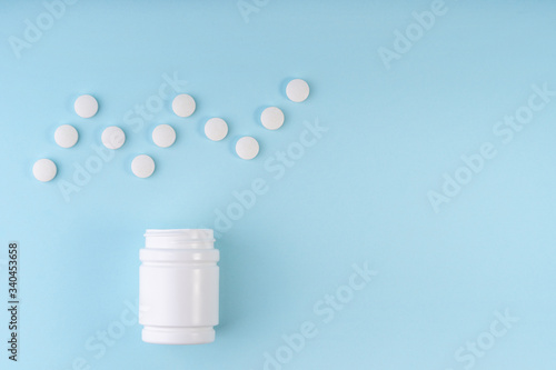 Cardiogram sign, heartbeat symbol from pharmaceutical medicine pills. Creative layout of tablets and bottle on blue. Medicine; healthcare concept. Copy space; flat lay