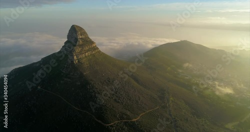 Aerial shot of a beautiful mountain peak over a scenic town, drone flying backwards - Cape Town, South Africa