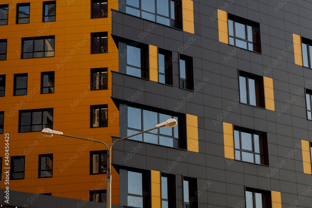 Yellow-brown modern ventilated facade with windows. Fragment of a new elite residential building or commercial complex.