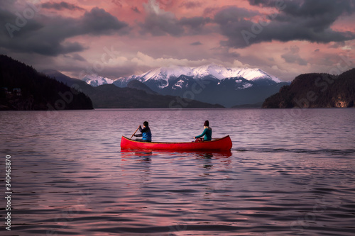 Fantasy Image Composite of Adventurous People on a Wooden Red Canoe during a Pink Cloudy Sunset. Landscape from Harrison Lake, British Columbia, Canada.