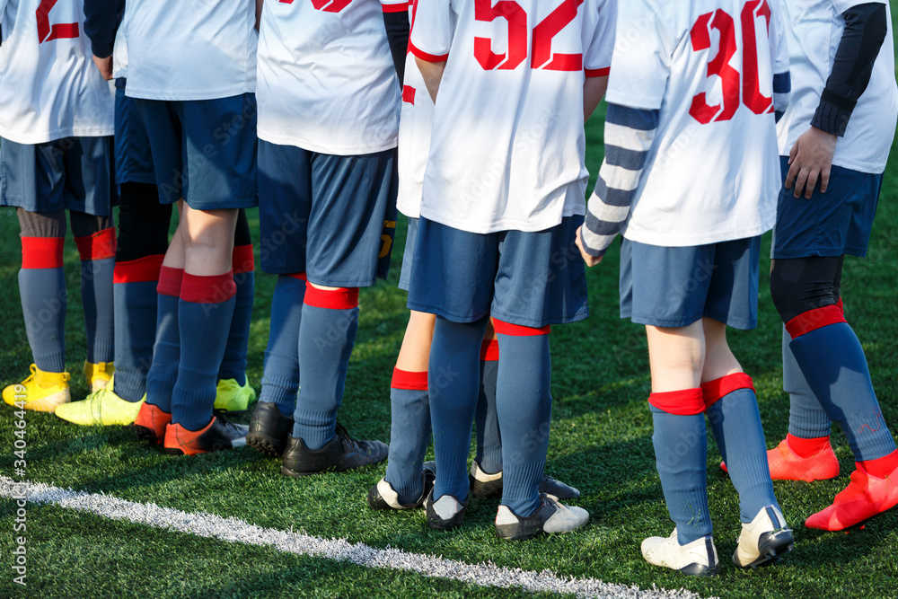 Fototapeta premium Boys in white sportswear running on soccer field. Young footballers dribble and kick football ball in game. Training, active lifestyle, sport, children activity concept