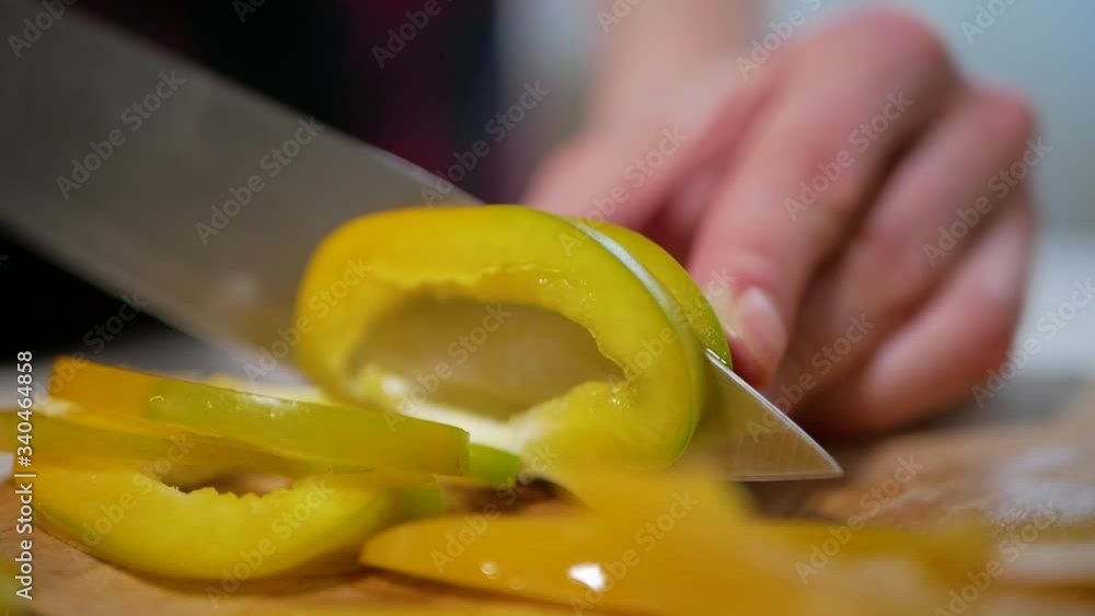 Young woman cuts pepper on a wooden cutting board, close-up Young woman cuts pepper on a wooden cutting board, close-up