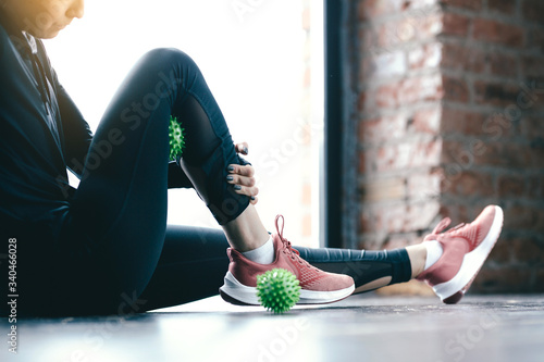 Close-up inflated legs in leggings. The girl leans a hip on the green Ball Myofascial. Massage of the thighs. photo