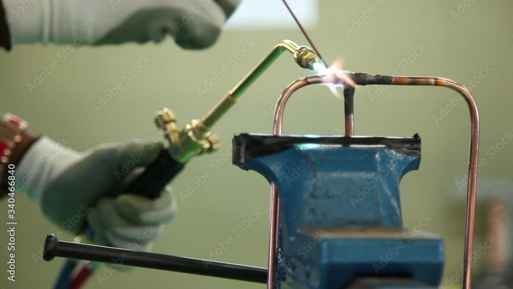 Plumber sweating a copper pipe with a propane torch to weld solder