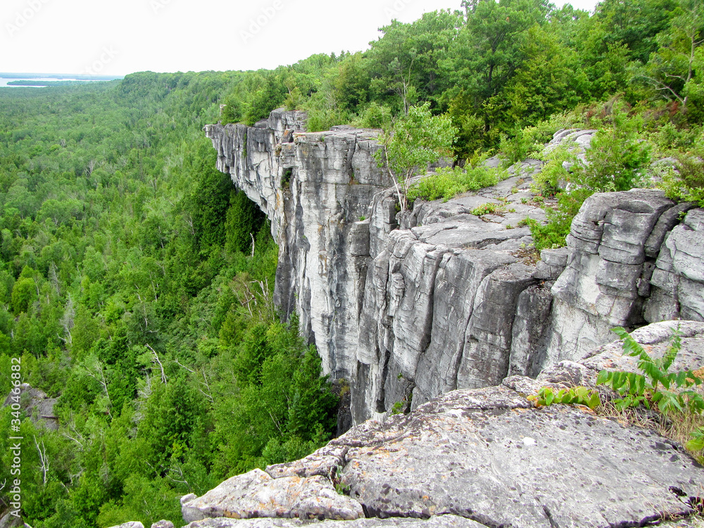 The edge of a raised rock mountain cliff side overlookign a forest on