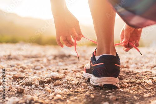 Woman wear running shoe on to walking and running on nature green background.Health exercise.