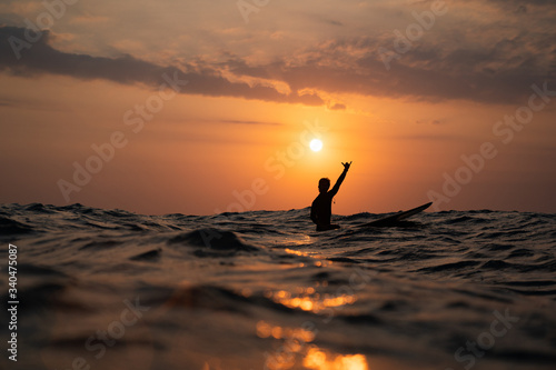 Fototapeta silhouette of a man surfing at sunset in the ocean