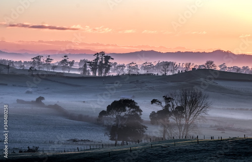 A beautiful pastel colored wintervsunrise over hills and fiels in rural New Zealand. 