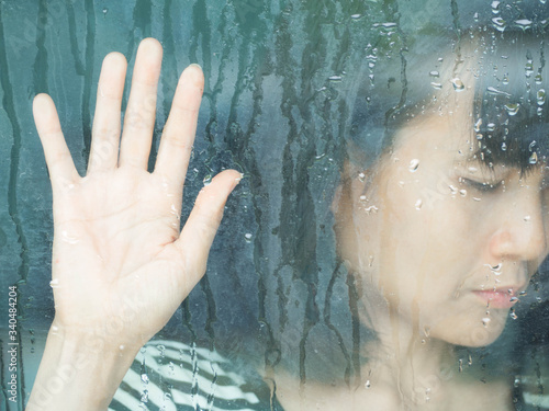 Close up woman cry through the window with the window in rainy. broken heart concept.