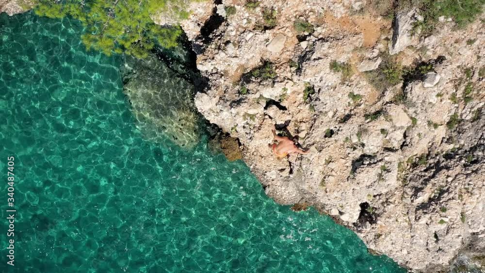 Aerial - Active muscular young athlete climbing the sea water cliff Aerial - Active muscular young athlete climbing the sea water cliff