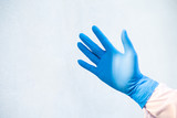 Hand put blue glove on white background.