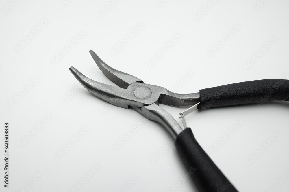 Curved nose pliers. Steel with black handles. Close up on white background. Curved nose pliers. Steel with black handles. Close up on white background.