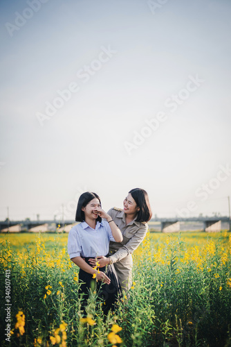 Young Asian Teacher with students  walking through Crotalaria flower field and enjoy at sunset © yupachingping