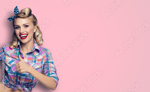 Pin up girl. Excited happy lovely woman showing thumb up gesture or like sign. Retro fashion and vintage. Pink color background. Copy space for some slogan, imaginary or text.