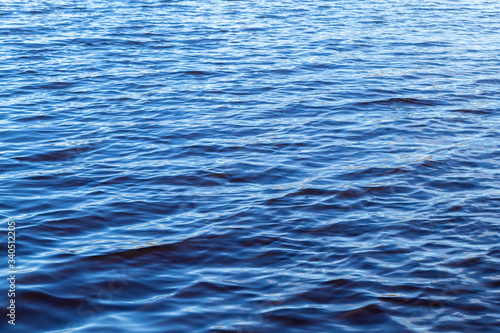 Small waves on the surface of the lake. Beautiful texture of blue water. On a sunny day