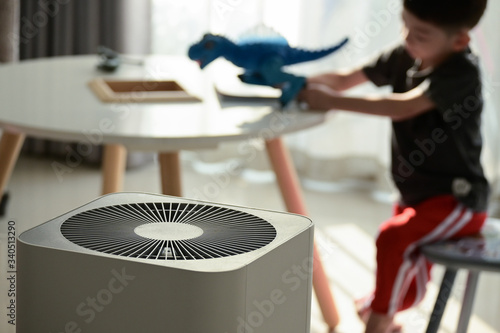 air purifier in living room with kid playing inside home photo