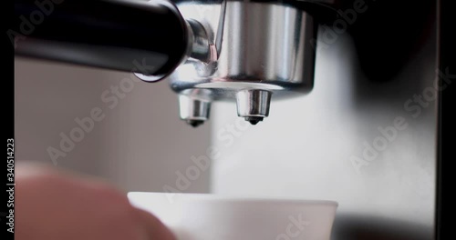 Pouring coffee stream from professional machine in cup. Barista man making double espresso, using filter holder. Flowing fresh ground coffee. Drinking roasted black coffee in the morning