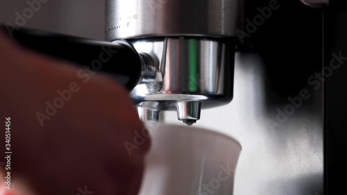Pouring coffee stream from professional machine in cup. Barista man making double espresso, using filter holder. Flowing fresh ground coffee. Drinking roasted black coffee in the morning