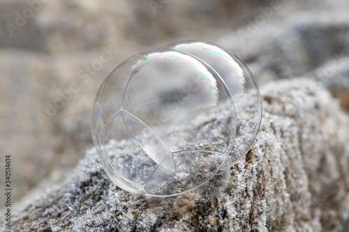 Mehrere leicht vereiste Seifenblasen auf einem vereisten Stein