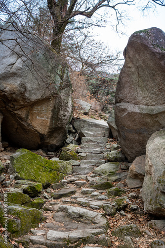Stone stairs in between two rocks in Bukhansan National Park near Seoul in South Korea on a cloudy winter day