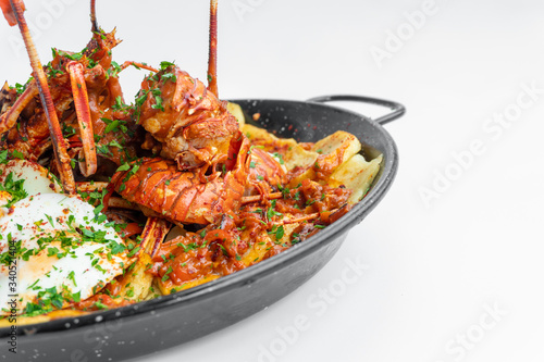 Formentera Lobster with fried potatoes, eggs and parsley in a traditional paella pan. Caldereta de bogavante de Formentera