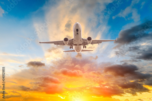 Commercial airplane flying in beautiful sky at sunset travel concept.