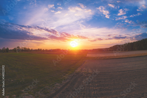 Spring rural landscape in the evening with beautiful sky, aerial view. Panoramic view of village and lake during sunset. Panorama from 9 images