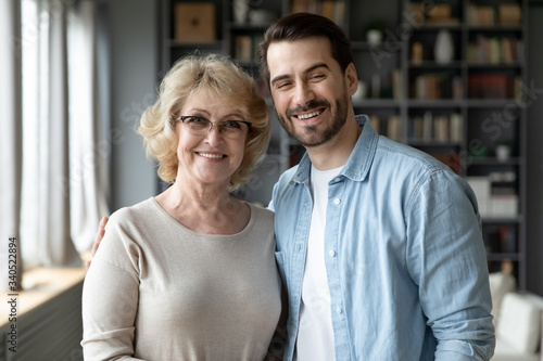 Fényképezés Happy senior mother in eyeglasses and bearded grown up son standing posing looking at camera