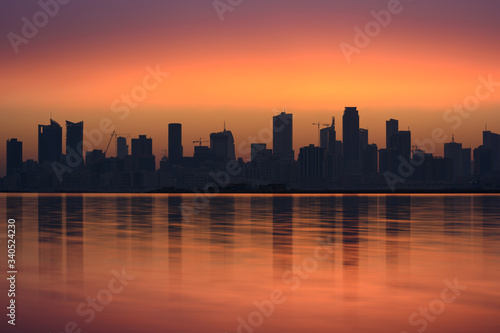 Silhouette of high rise buildings in Seef district during sunrise with beautiful reflections, Manama, Bahrain