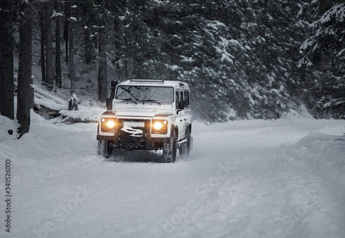 vintage sport utility vehicle driving during snow storm in forest © AlexGo