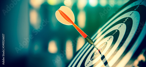 Bullseye(bull's-eye) or dart board has dart arrow hitting the center of a shooting target for business targeting and and marketing goal concetps.