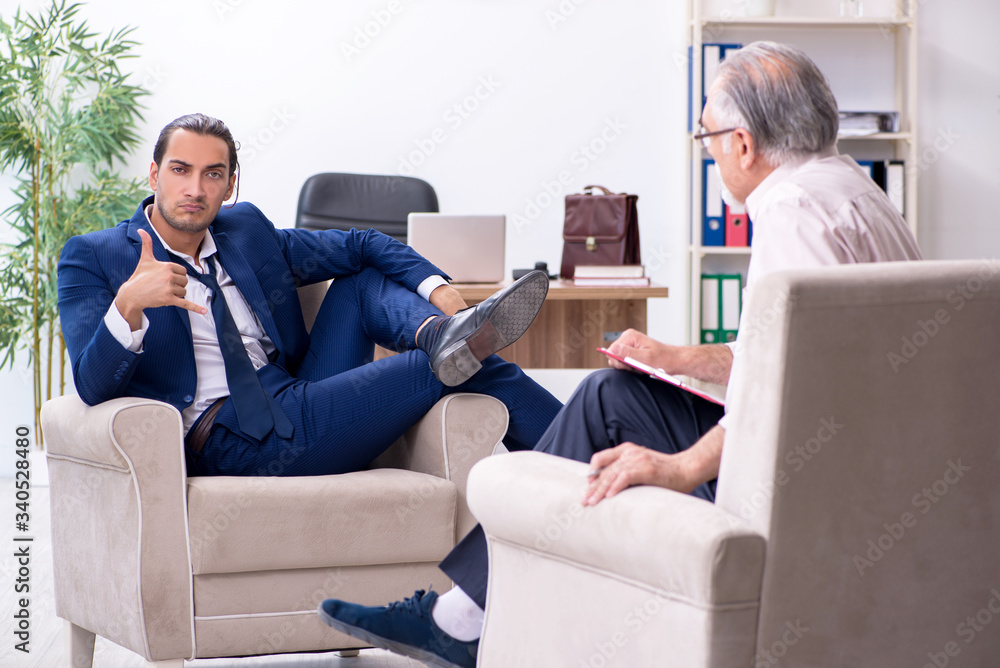 Young man visiting old male doctor psychologist Young man visiting old male doctor psychologist