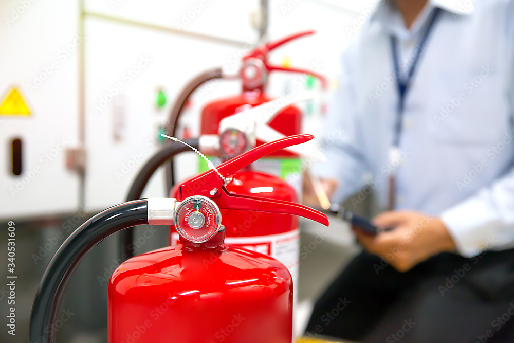 Fireman are checking and inspection red tank of fire extinguisher.Concepts of Emergency and safety equipment for fire prevention and training on the use of fire extinguishers.