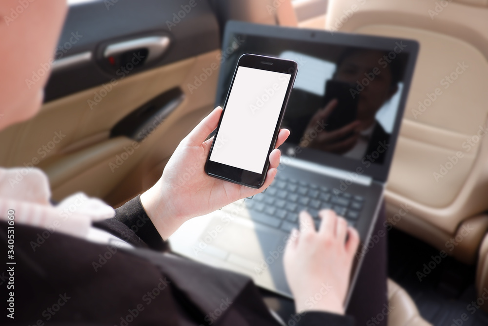 Cropped shot view of young businesswoman using laptop and smart phone  in a car.