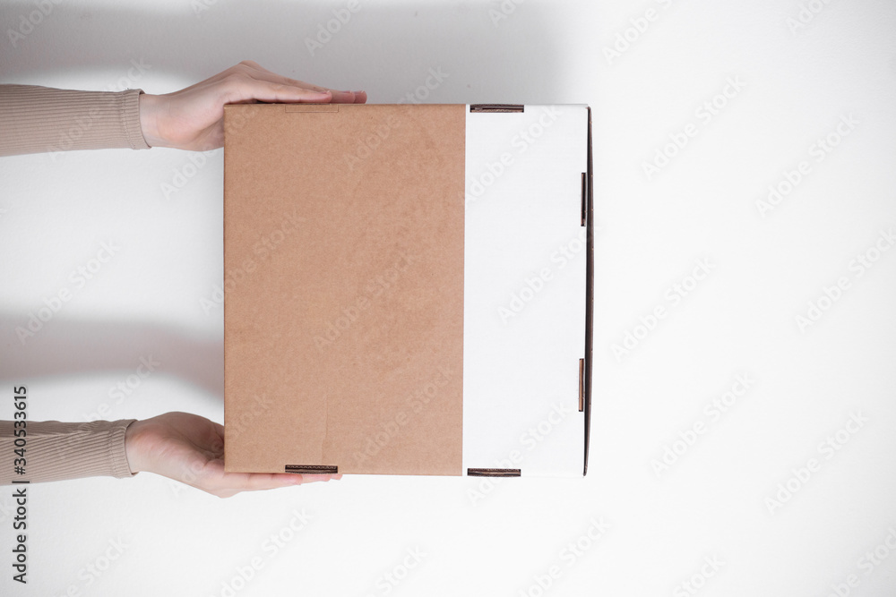A parcel cardboard box in a delivery man hands on a white background. Delivery service concept. A parcel cardboard box in a delivery man hands on a white background. Delivery service concept.