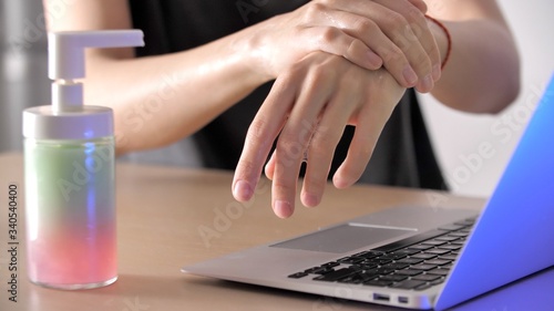 Woman s hands rubs his hands with a sanitizer and works with a laptop. Coronavirus or Covid-19. Woman are typing on a keyboard on a laptop close-up. Stay home to work.