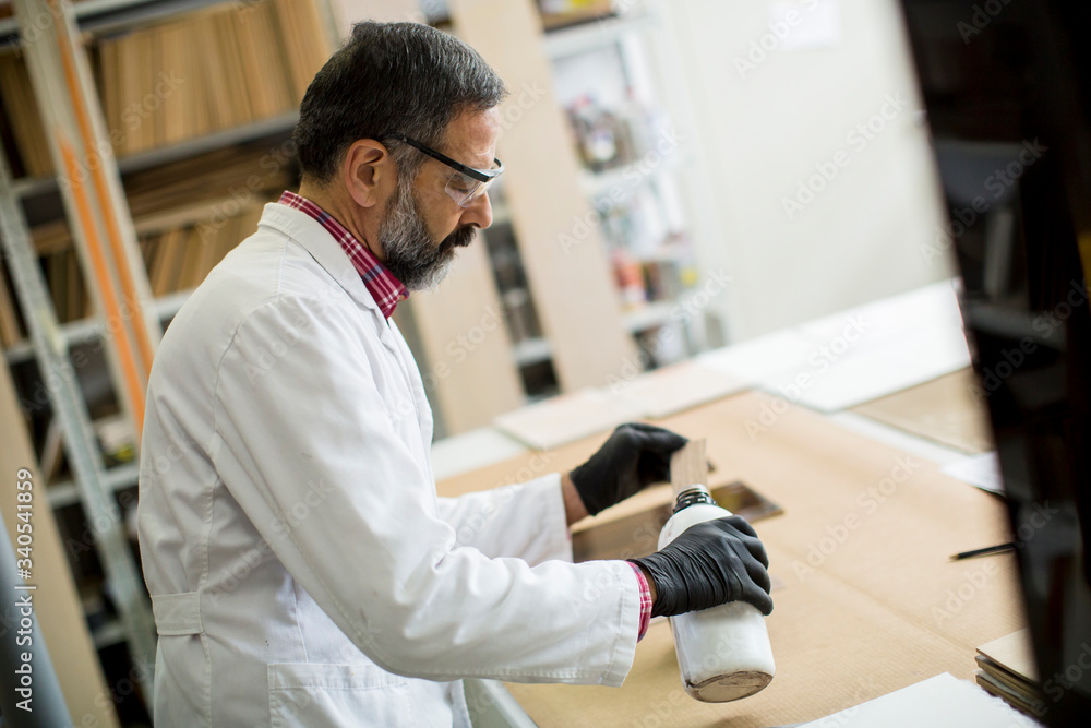 Handsome mature engineer in the laboratory examines ceramic tiles Handsome mature engineer in the laboratory examines ceramic tiles