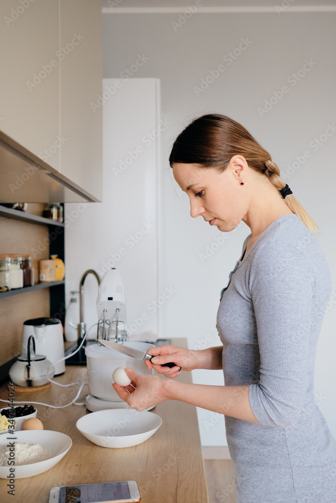 Beautiful woman break chicken eggs in a plate in the kitchen. Cooking dough. Beautiful woman break chicken eggs in a plate in the kitchen. Cooking dough.