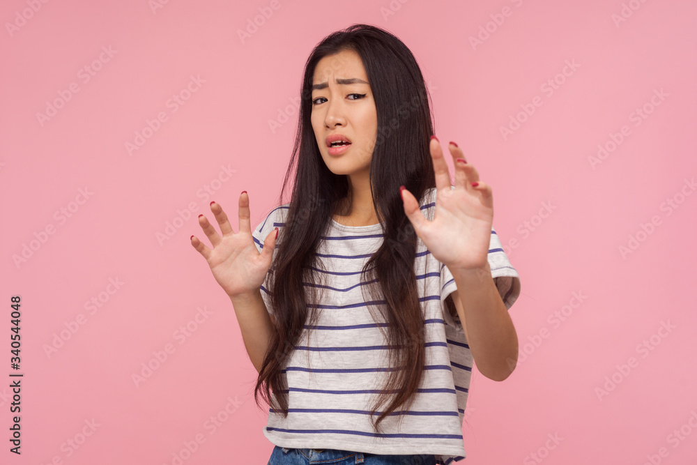 I'm scared! Portrait of panicking girl with long brunette hair in striped t-shirt expressing fear, holding hands up, looking terrified as noticing something terrible. indoor studio shot isolated I'm scared! Portrait of panicking girl with long brunette hair in striped t-shirt expressing fear, holding hands up, looking terrified as noticing something terrible. indoor studio shot isolated