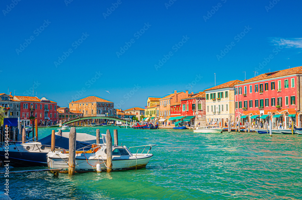 Murano islands with bridge across water canal, boats and motor boats, colorful traditional buildings, Venetian Lagoon, Province of Venice, Veneto Region, Northern Italy. Murano postcard cityscape.