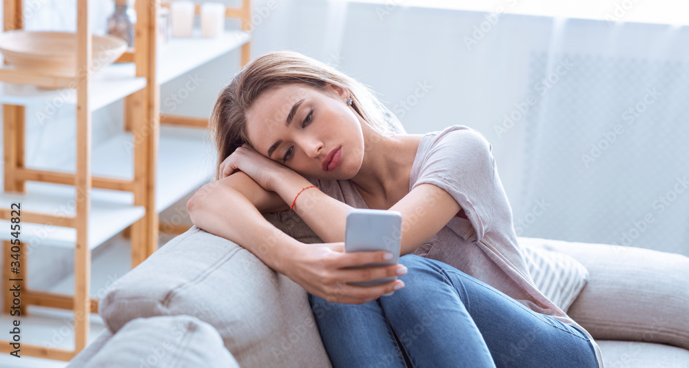 Bored girl surfing at internet on smartphone Bored girl surfing at internet on smartphone