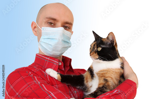 young man in a white medical antivirus mask holds a domestic dark cat in his hands, the concept of coronavirus COVID-19 in humans and animals, veterinary medicine © kittyfly