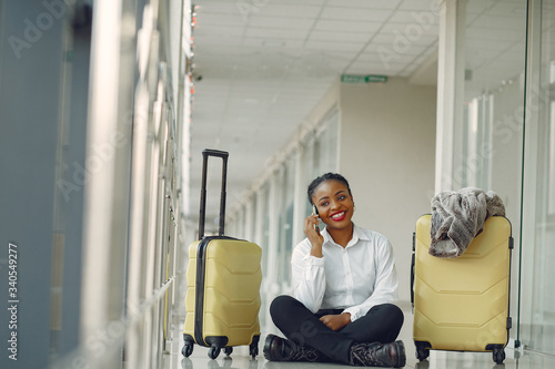 Black woman at the airport. Girl with suitcase. Lady in a white shirt.