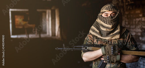 Arab male soldier in a headdress from the national keffiyeh with a weapon in his hands man with a gun on a black background photo