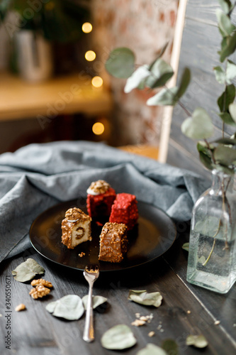 Fototapeta Naklejka Na Ścianę i Meble -  a piece of sliced cupcake in colored chocolate glaze served on a black plate a stylish composition with walnuts
