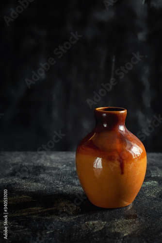 orange clay vase on a black background
